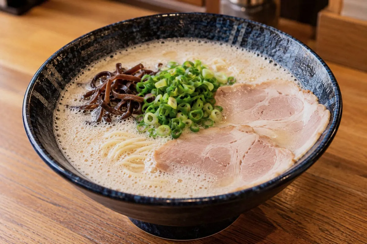 Hakata Ikkousha frothy tonkotsu ramen in a dark-blue bowl, with milky-white foamy broth, chashu pork, and spring onions