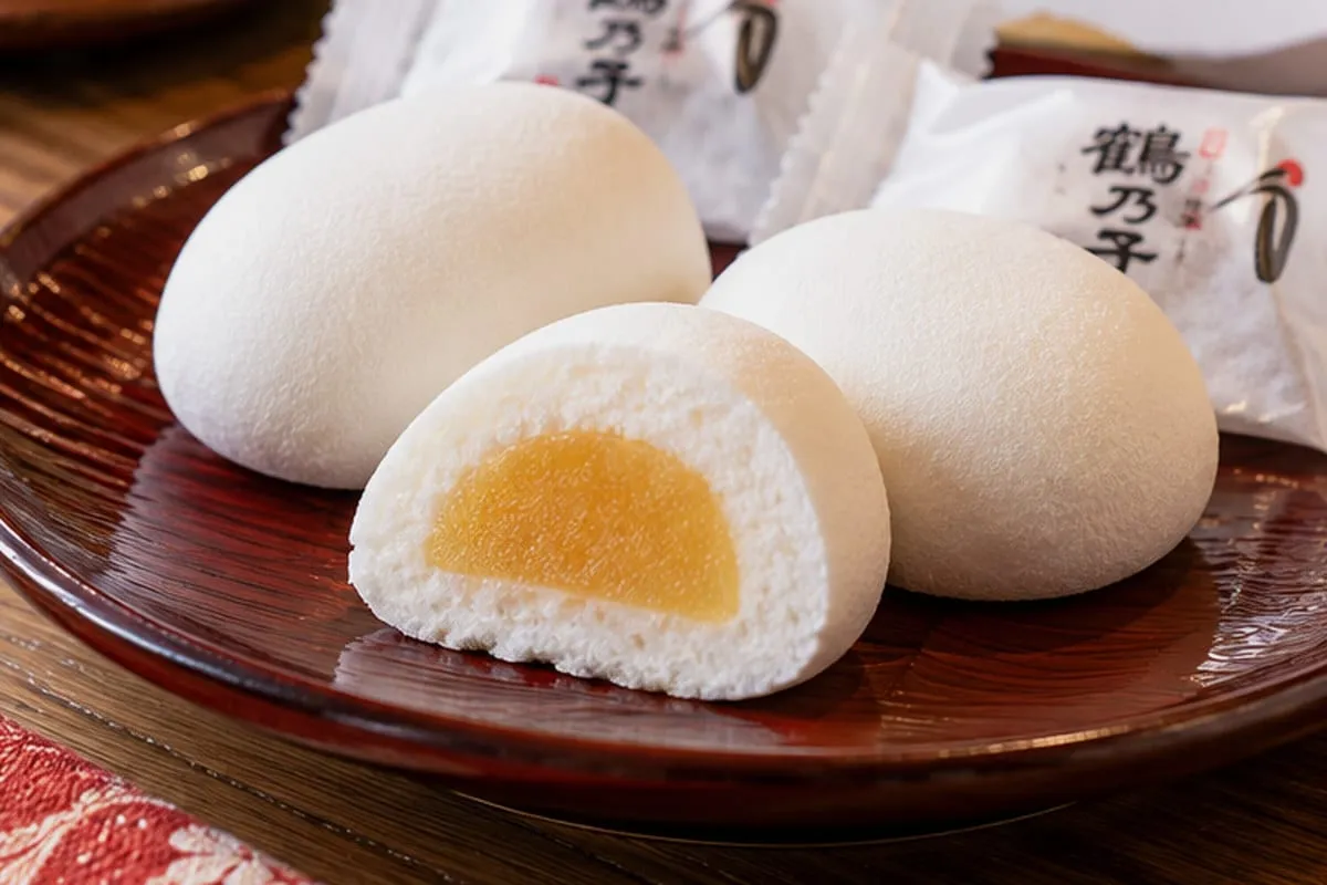 Tsuru no Ko: egg-shaped sweets with a white marshmallow exterior and yellow filling, next to printed packaging